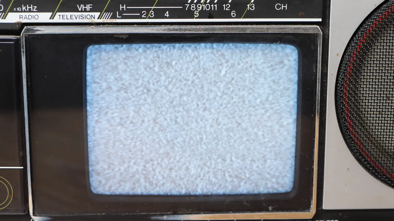 A screen full of static on an old beat up black-and-white TV screen (a small one integrated into a boombox)