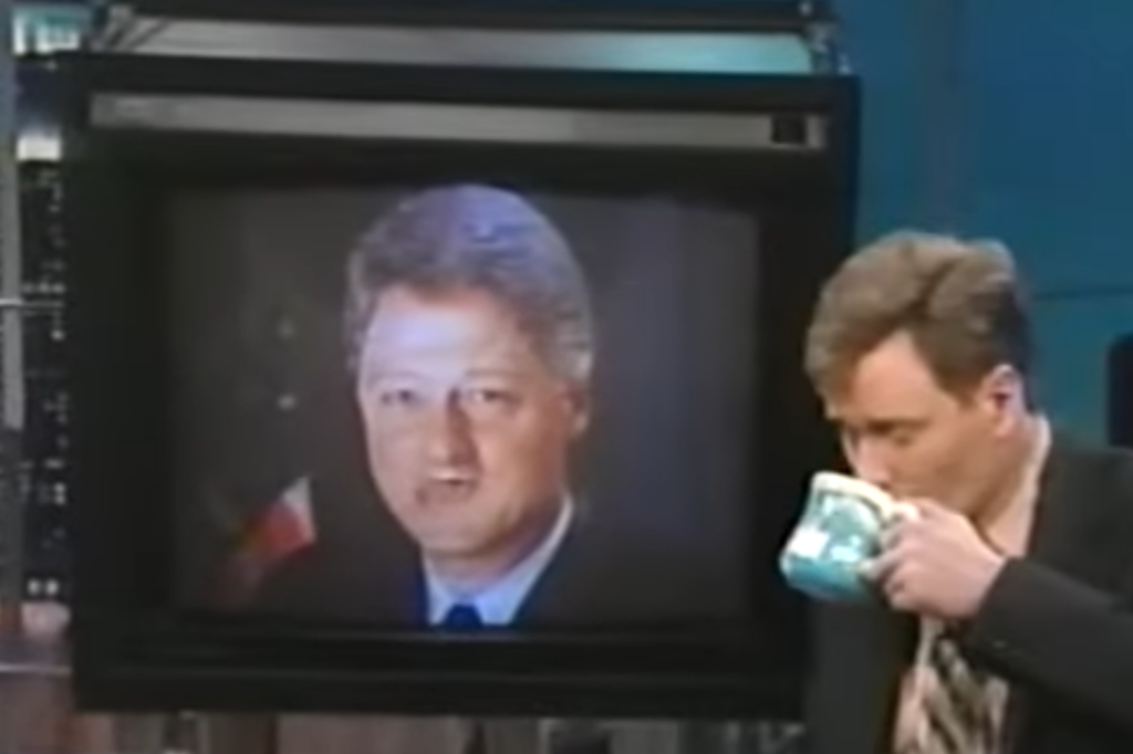 A photo of a 90s episode of Conan O'Brien: Bill Clinton's face is on a TV screen but his mouth has been replaced with another mouth. Conan is to the side of the TV sipping coffee.